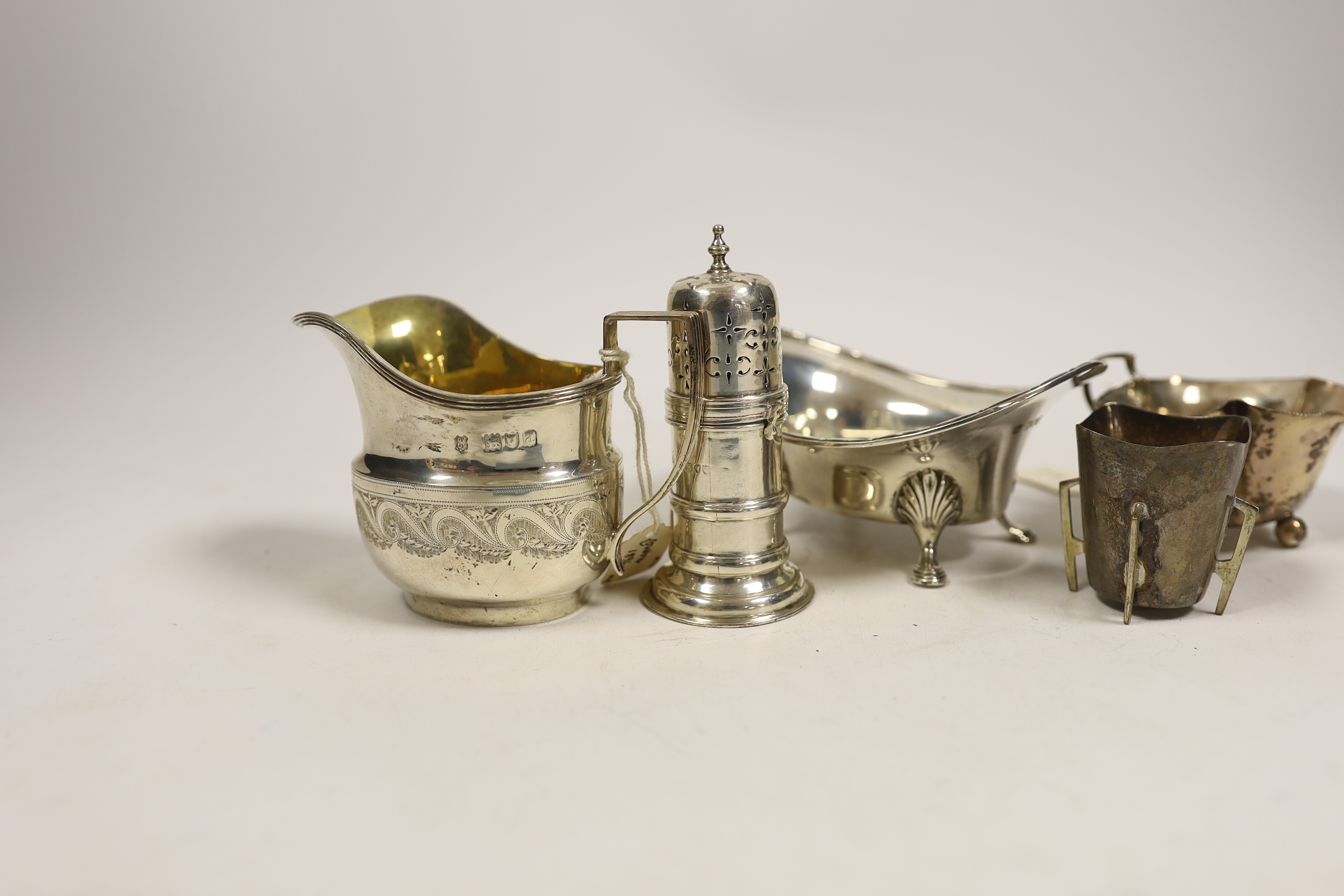 Small silverware, consisting:- a late Victorian helmet shaped cream jug, 1896; a George V oval sugar bowl, a late Victorian lighthouse sugar caster, 91mm, an Edwardian silver cream jug, 1908 and a silver tot.